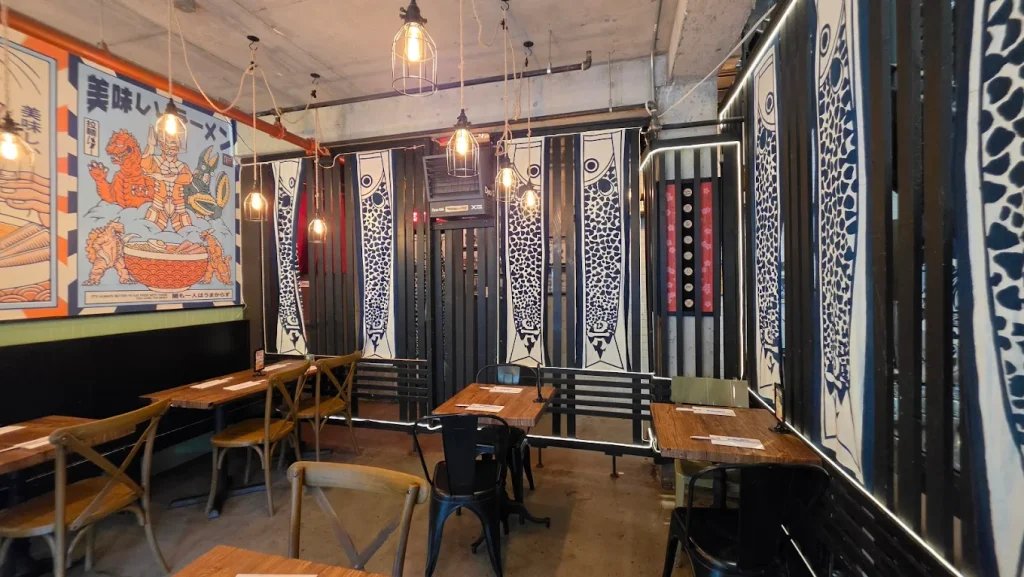 Japanese wall decor, soft lighting, wooden tables, and chairs. 